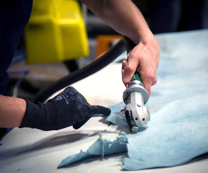 Artisan découpant un matériau à l’aide d’un outil électrique portatif.
