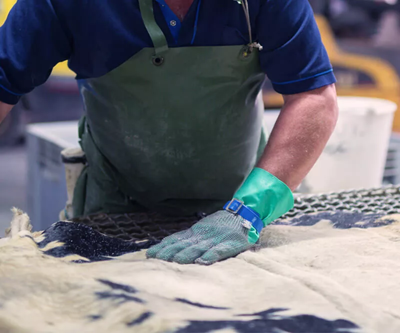 Artisan en train de travailler manuellement une pièce de cuir sur une table.