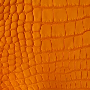 Gros plan sur un cuir de crocodile orange avec un motif écailleux.