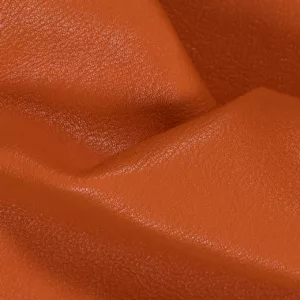 Gros plan sur une texture de cuir de chèvre lisse avec des grains visibles et des plis.