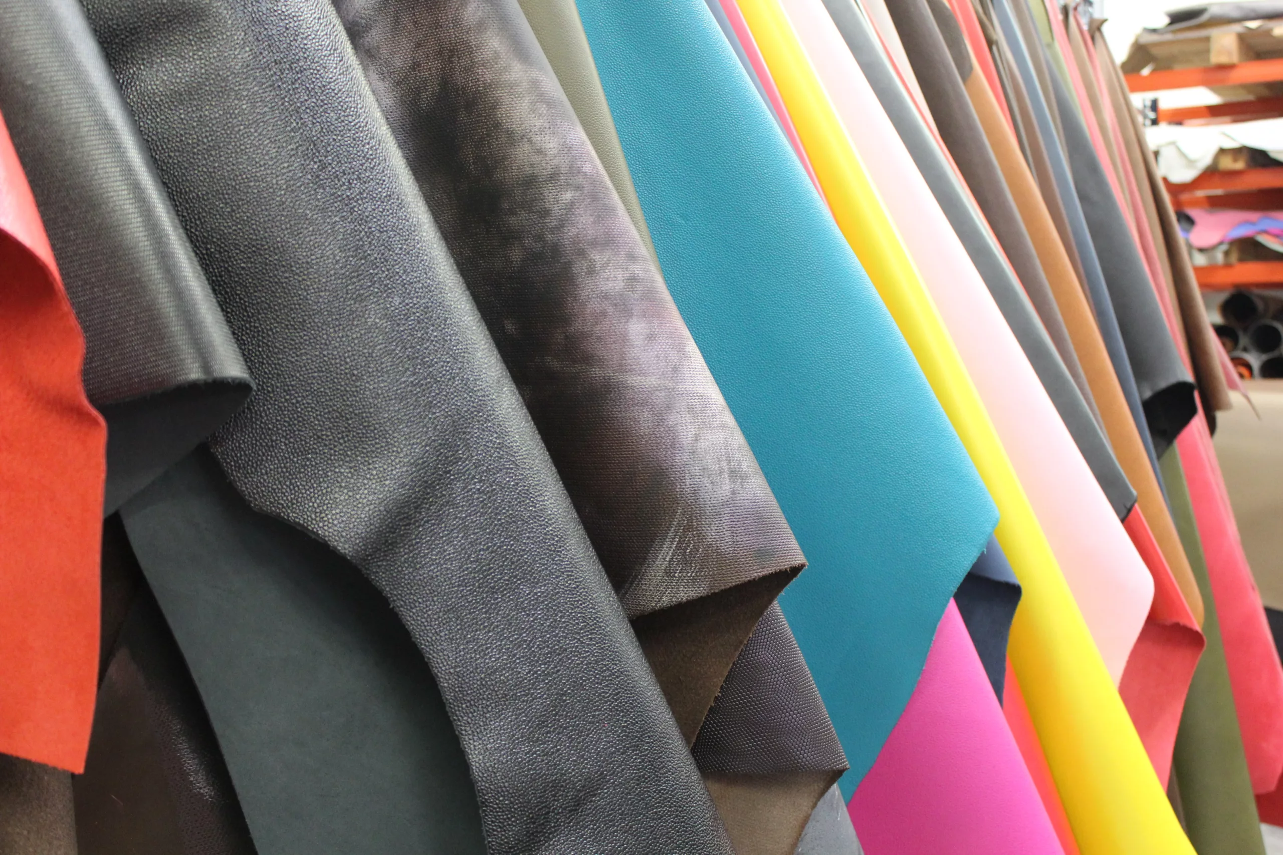 Cuirs de veau pleine fleur multicolores suspendus, exposant leurs textures et finitions variées.