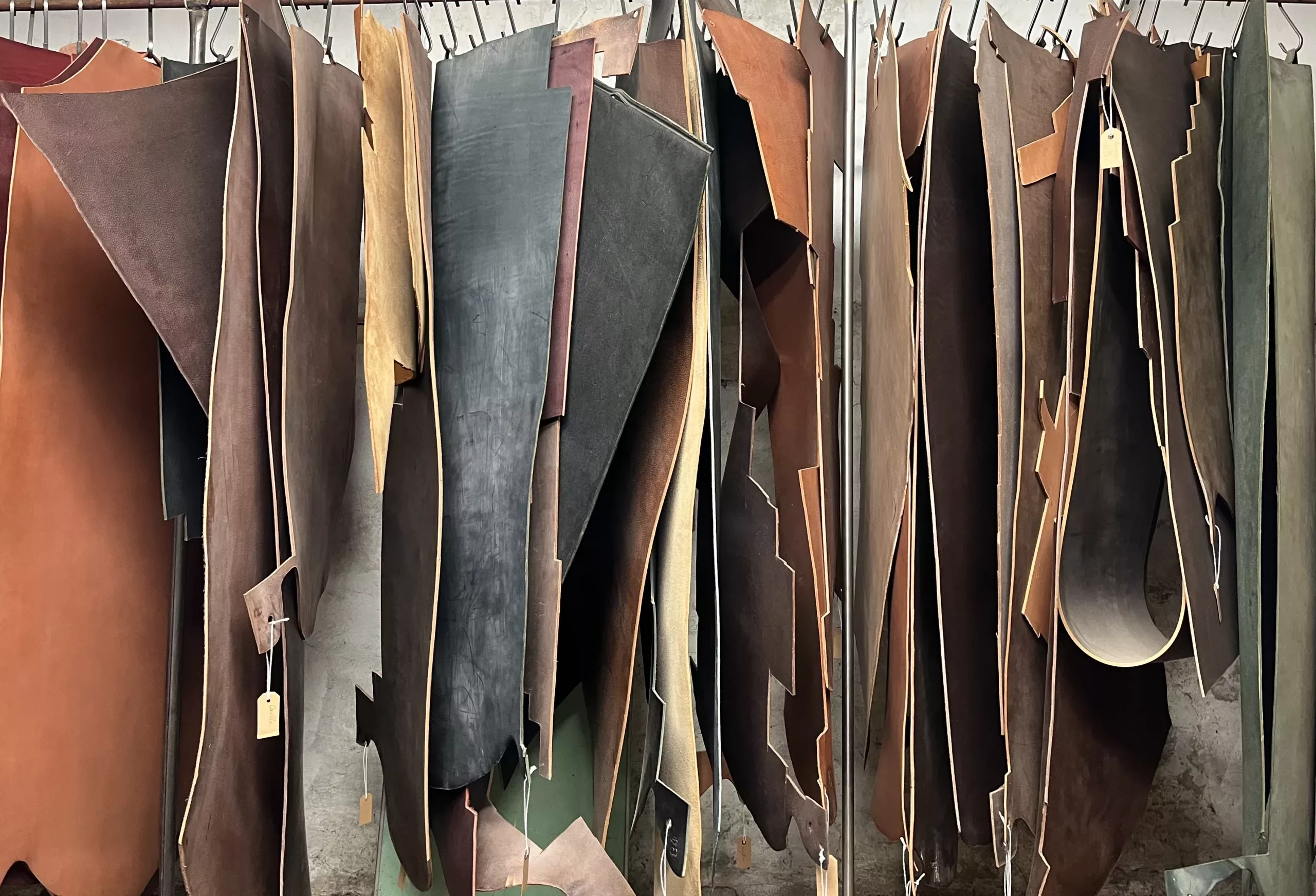 Various pieces of bovine leather hanging and suspended from a rod.