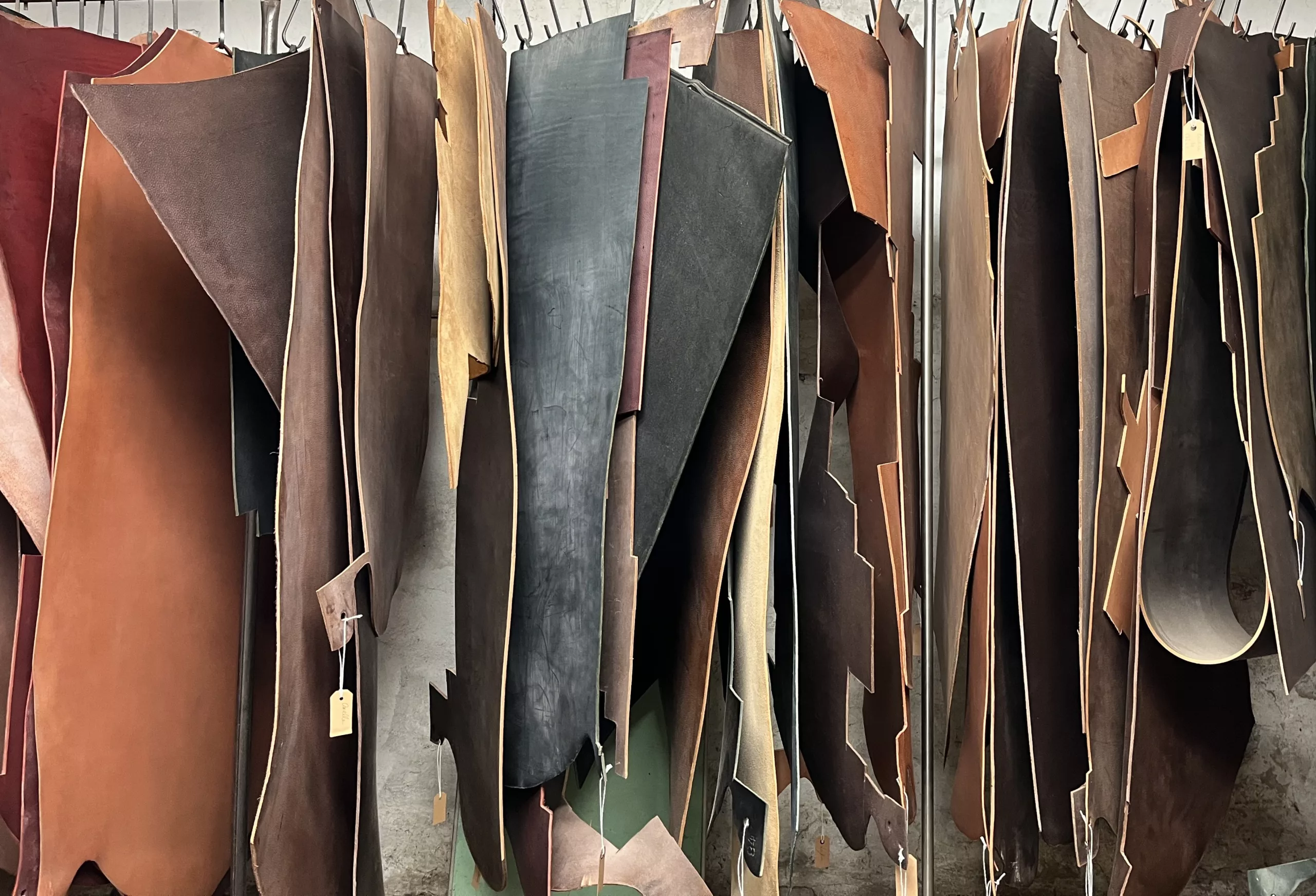 Vari pezzi di pelle bovina appesi e sospesi a una barra.